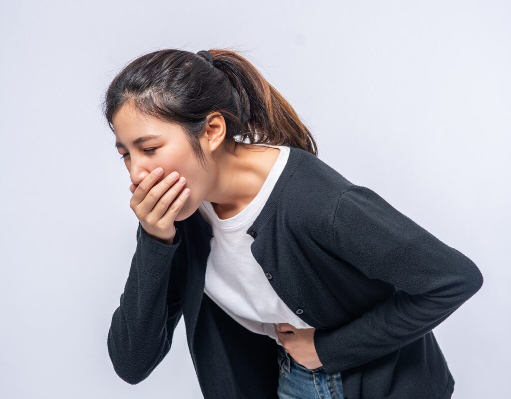 A person holding their stomach with a pained expression, representing the discomfort of nausea
